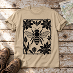 Biene im Blütenrahmen – T-Shirt Unisex in Sand, flach liegend auf alten Holzbrettern mit Wanderschuhen und Wanderkarte.