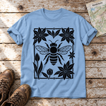 Biene im Blütenrahmen – T-Shirt Unisex in Himmelblau, flach liegend auf alten Holzbrettern mit Wanderschuhen und Wanderkarte.