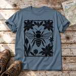 Biene im Blütenrahmen – T-Shirt Unisex in Steinblau, flach liegend auf alten Holzbrettern mit Wanderschuhen und Wanderkarte.