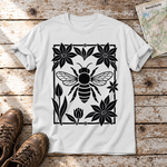 Biene im Blütenrahmen – T-Shirt Unisex in Weiß, flach liegend auf alten Holzbrettern mit Wanderschuhen und Wanderkarte.