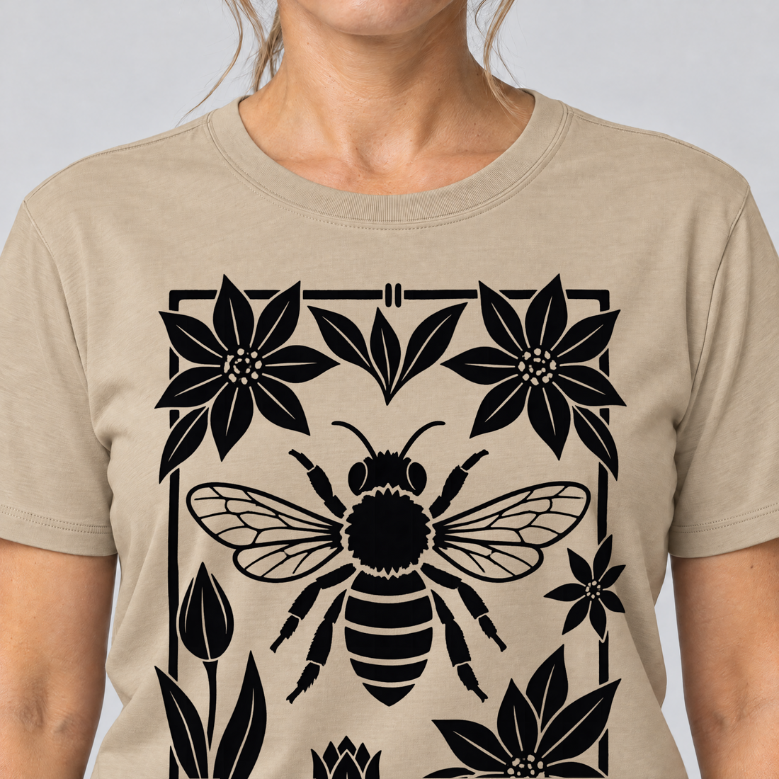 Nahaufnahme des Drucks: Biene im Blütenrahmen – T-Shirt Unisex in Sand, von einer Frau getragen