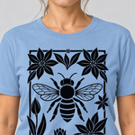 Nahaufnahme des Drucks: Biene im Blütenrahmen – T-Shirt Unisex in Himmelblau, von einer Frau getragen
