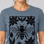 Nahaufnahme des Drucks: Biene im Blütenrahmen – T-Shirt Unisex in Steinblau, von einer Frau getragen