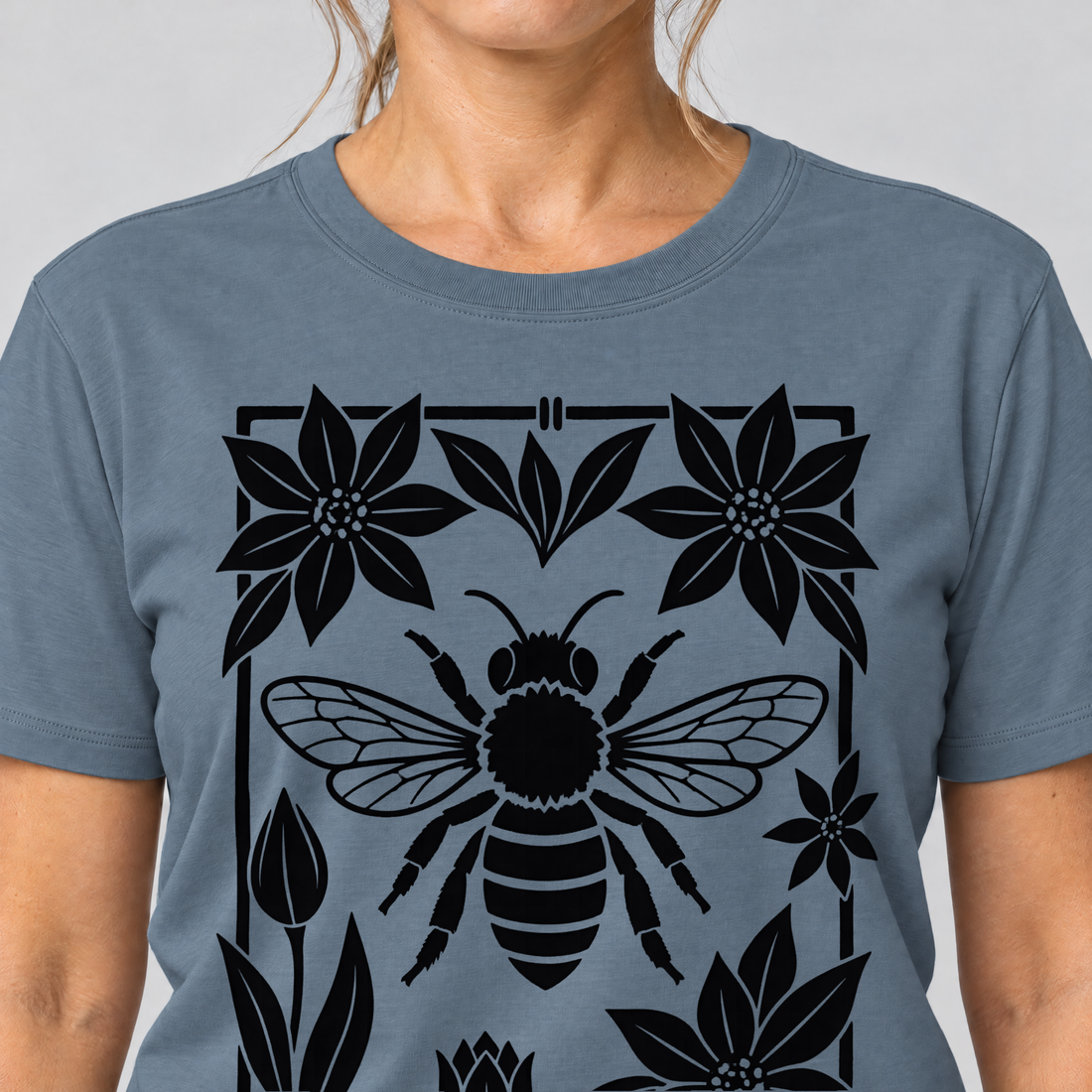 Nahaufnahme des Drucks: Biene im Blütenrahmen – T-Shirt Unisex in Steinblau, von einer Frau getragen