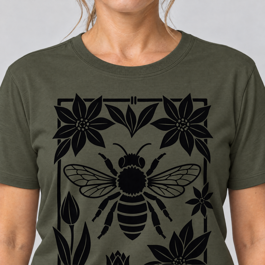 Nahaufnahme des Drucks: Biene im Blütenrahmen – T-Shirt Unisex in Oliv, von einer Frau getragen