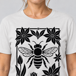 Nahaufnahme des Drucks: Biene im Blütenrahmen – T-Shirt Unisex in Weiß, von einer Frau getragen