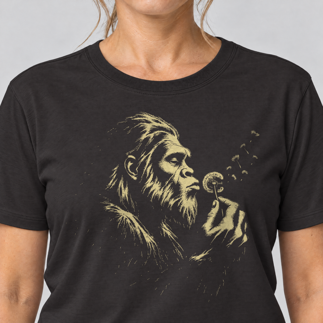 Nahaufnahme des Drucks: Bigfoot mit Pusteblume – T-Shirt Unisex in Schwarz, von einer Frau getragen