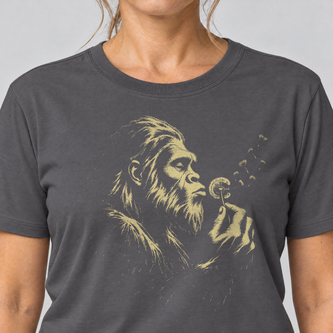 Nahaufnahme des Drucks: Bigfoot mit Pusteblume – T-Shirt Unisex in Dunkelgrau, von einer Frau getragen