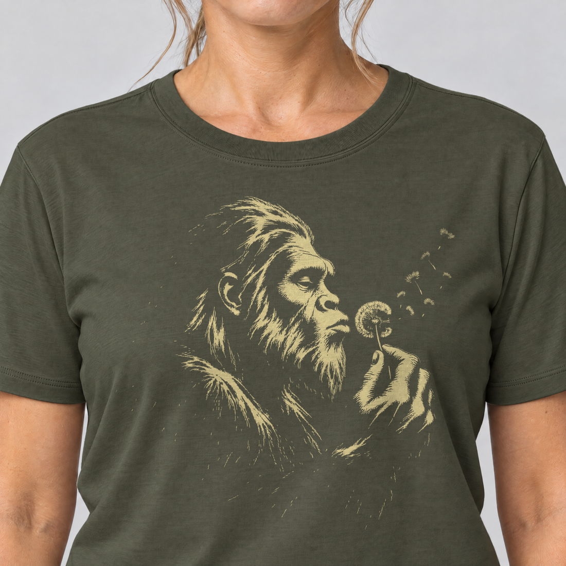 Nahaufnahme des Drucks: Bigfoot mit Pusteblume – T-Shirt Unisex in Oliv, von einer Frau getragen