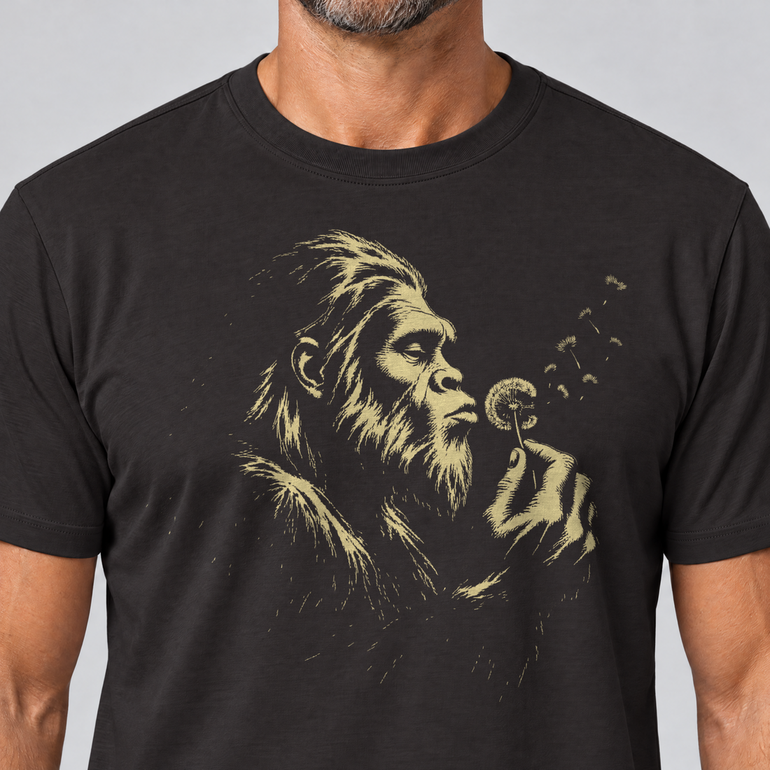Nahaufnahme des Drucks: Bigfoot mit Pusteblume – T-Shirt Unisex in Schwarz, von einem Mann getragen