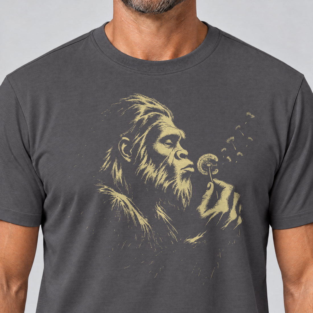 Nahaufnahme des Drucks: Bigfoot mit Pusteblume – T-Shirt Unisex in Dunkelgrau, von einem Mann getragen