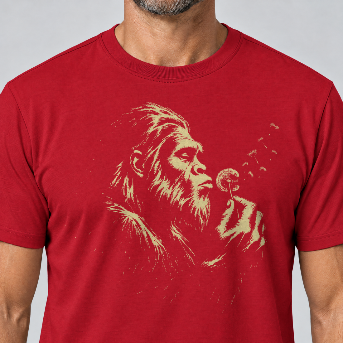 Nahaufnahme des Drucks: Bigfoot mit Pusteblume – T-Shirt Unisex in Rot, von einem Mann getragen