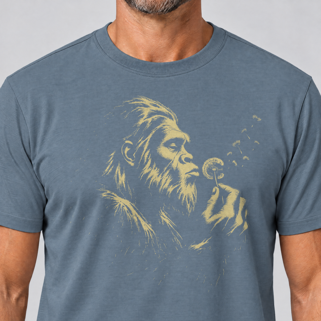 Nahaufnahme des Drucks: Bigfoot mit Pusteblume – T-Shirt Unisex in Steinblau, von einem Mann getragen