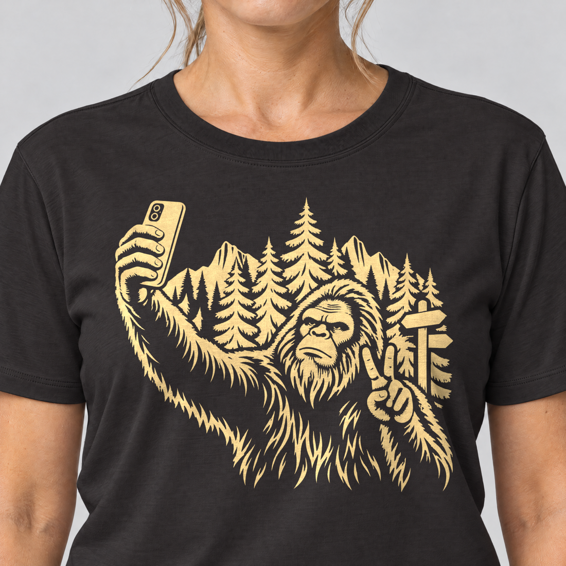 Nahaufnahme des Drucks: Bigfoot-Selfie im Bergwald – T-Shirt Unisex in Schwarz, von einer Frau getragen