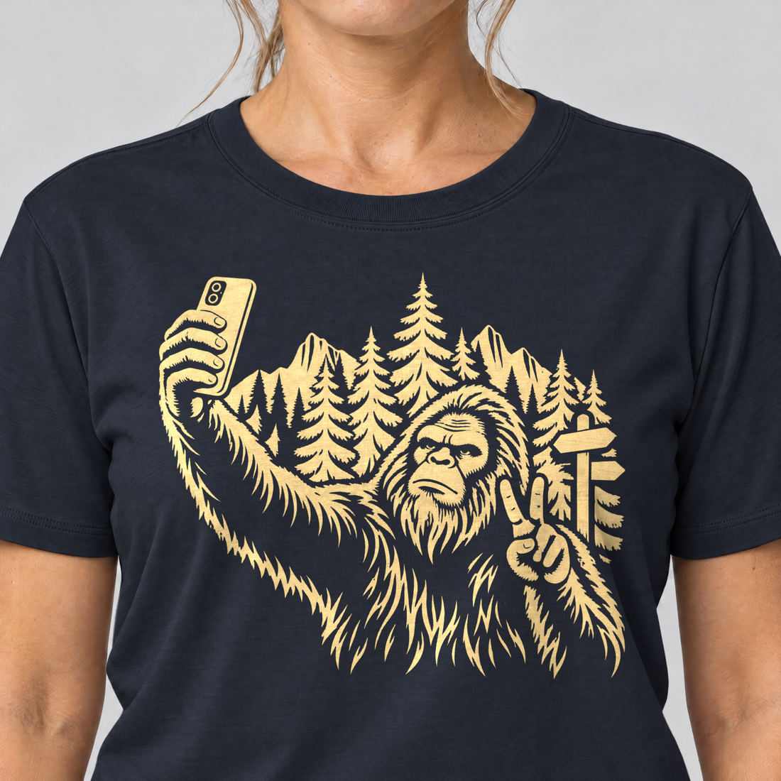 Nahaufnahme des Drucks: Bigfoot-Selfie im Bergwald – T-Shirt Unisex in Navy, von einer Frau getragen