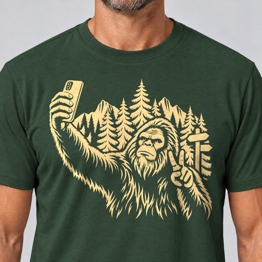 Nahaufnahme des Drucks: Bigfoot-Selfie im Bergwald – T-Shirt Unisex in Flaschengrün, von einem Mann getragen