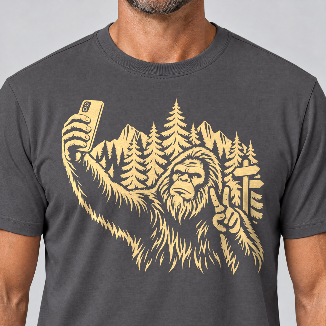 Nahaufnahme des Drucks: Bigfoot-Selfie im Bergwald – T-Shirt Unisex in Dunkelgrau, von einem Mann getragen