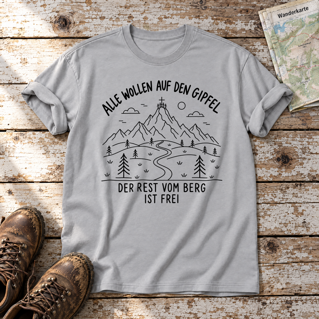Der Rest vom Berg ist frei – T-Shirt Unisex in Hellgrau, flach liegend auf alten Holzbrettern mit Wanderschuhen und Wanderkarte.
