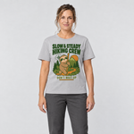 Frau trägt Slow & Steady Hiking Crew – T-Shirt Unisex in Hellgrau, Ansicht von vorn