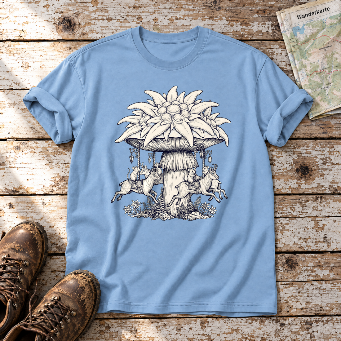 Edelweiß-Karussell – T-Shirt Unisex in Himmelblau, flach liegend auf alten Holzbrettern mit Wanderschuhen und Wanderkarte.