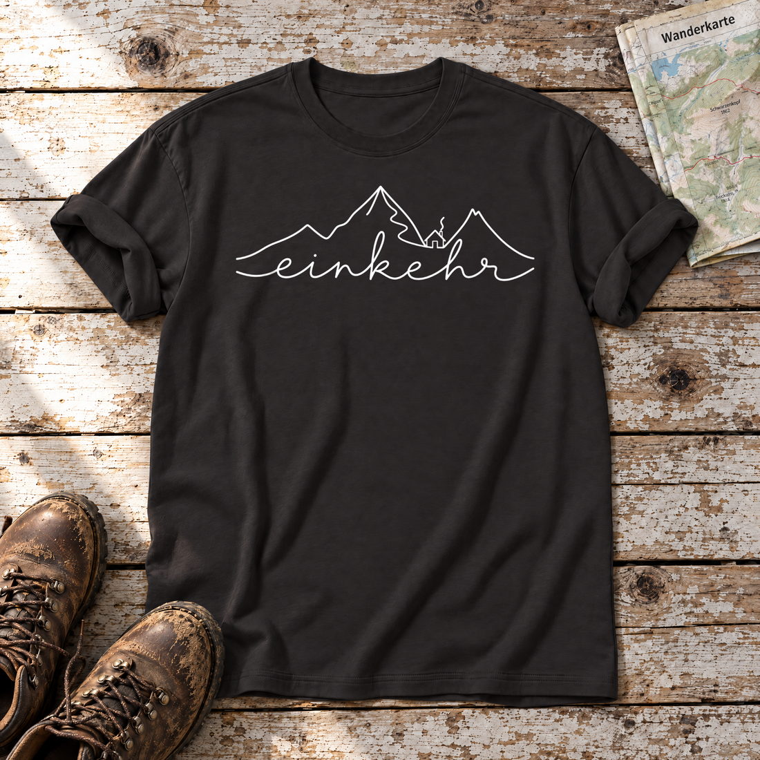 Einkehr – T-Shirt Unisex in Schwarz, flach liegend auf alten Holzbrettern mit Wanderschuhen und Wanderkarte.