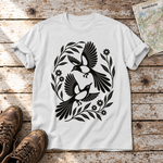 Elsternpaar im Scherenschnitt – T-Shirt Unisex in Weiß, flach liegend auf alten Holzbrettern mit Wanderschuhen und Wanderkarte.