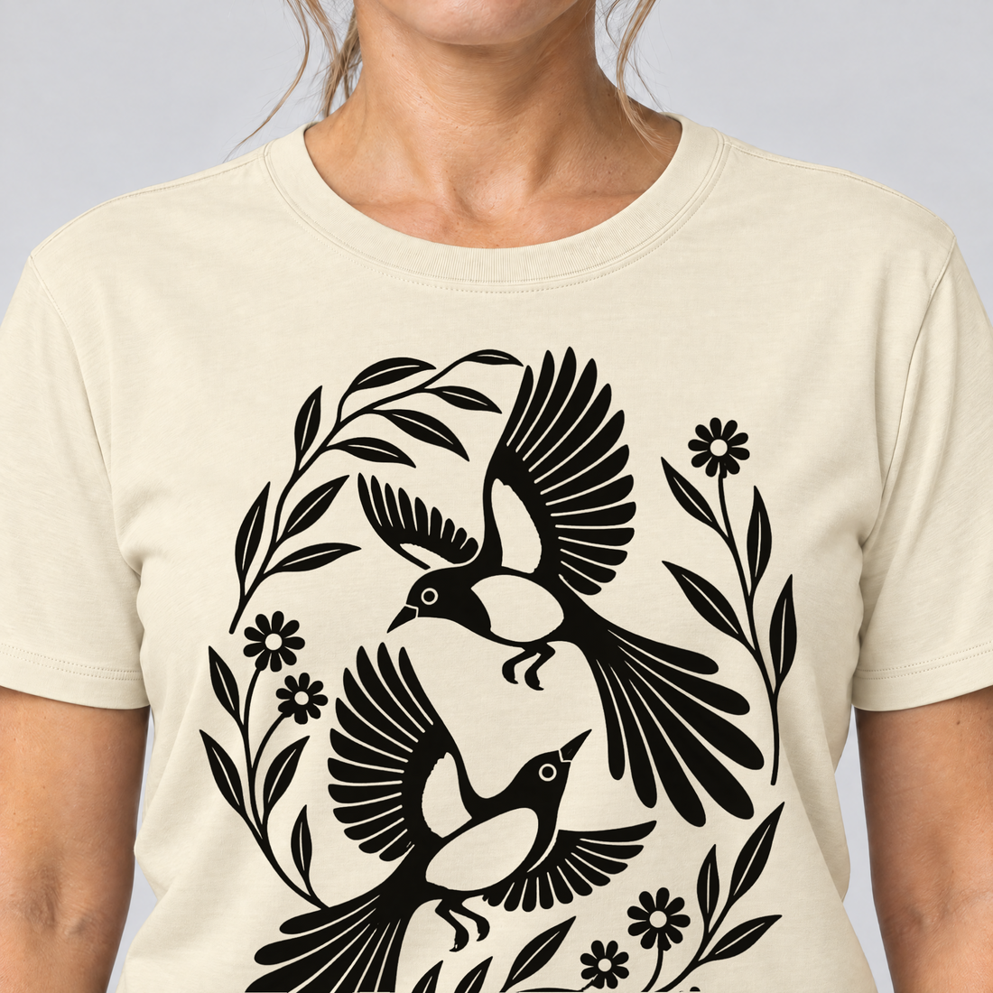 Nahaufnahme des Drucks: Elsternpaar im Scherenschnitt – T-Shirt Unisex in Natur, von einer Frau getragen