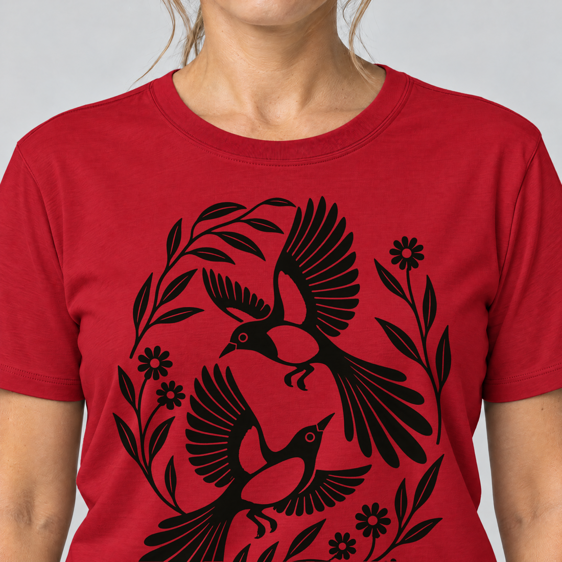 Nahaufnahme des Drucks: Elsternpaar im Scherenschnitt – T-Shirt Unisex in Rot, von einer Frau getragen