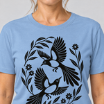 Nahaufnahme des Drucks: Elsternpaar im Scherenschnitt – T-Shirt Unisex in Himmelblau, von einer Frau getragen