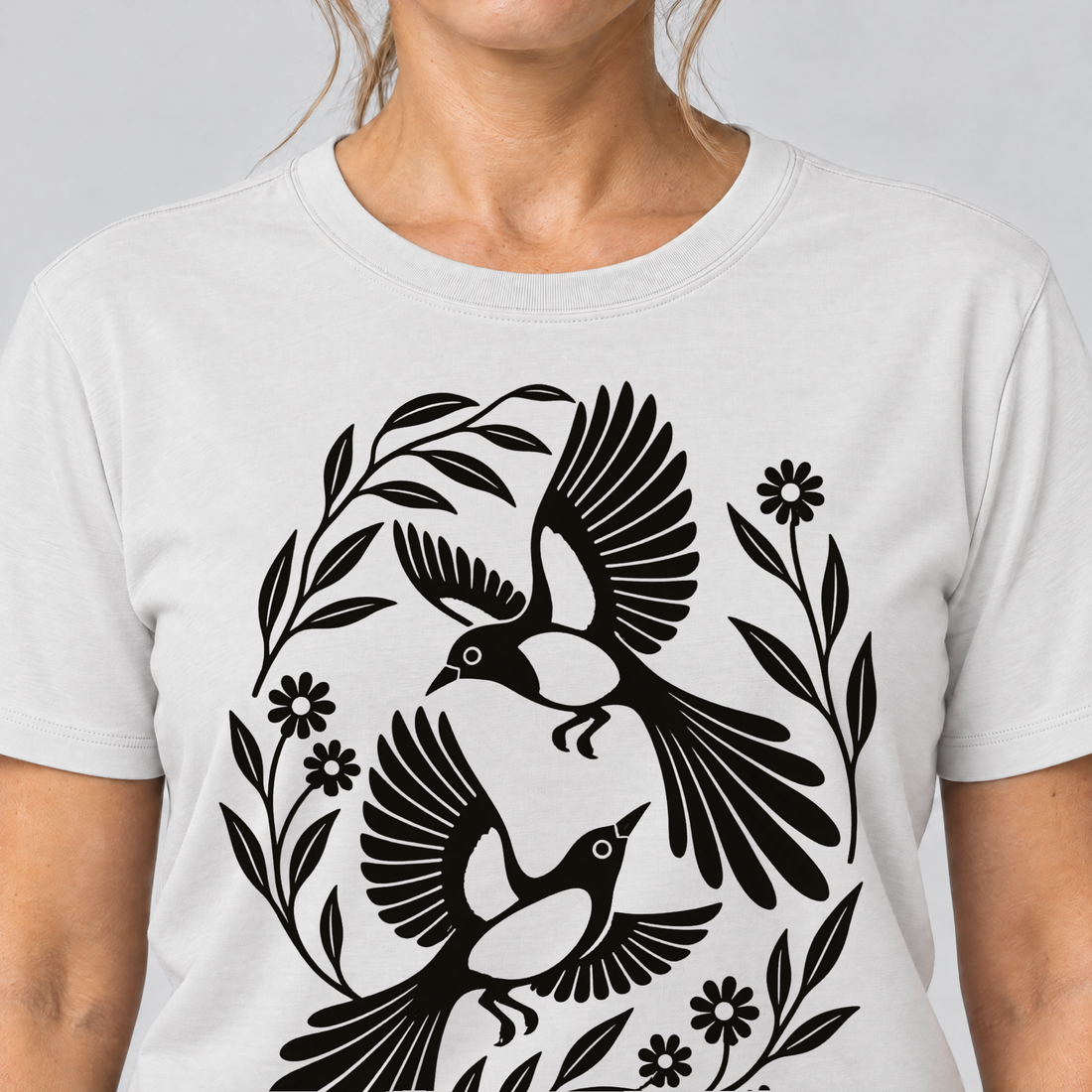 Nahaufnahme des Drucks: Elsternpaar im Scherenschnitt – T-Shirt Unisex in Weiß, von einer Frau getragen