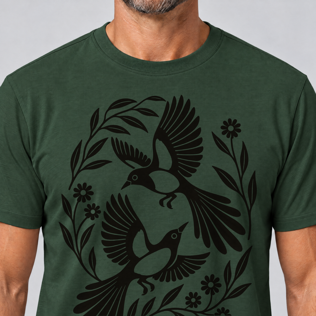 Nahaufnahme des Drucks: Elsternpaar im Scherenschnitt – T-Shirt Unisex in Flaschengrün, von einem Mann getragen