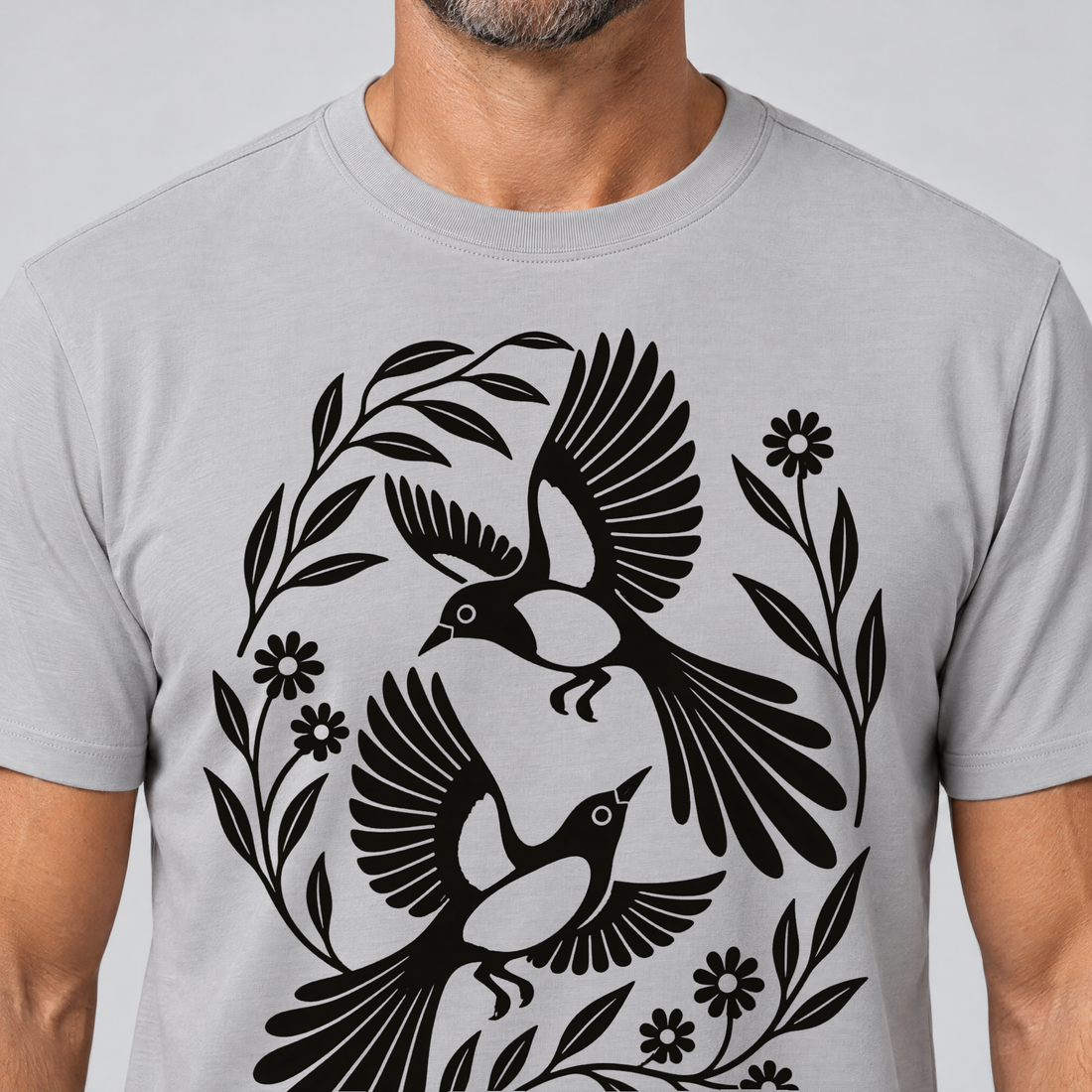 Nahaufnahme des Drucks: Elsternpaar im Scherenschnitt – T-Shirt Unisex in Hellgrau, von einem Mann getragen