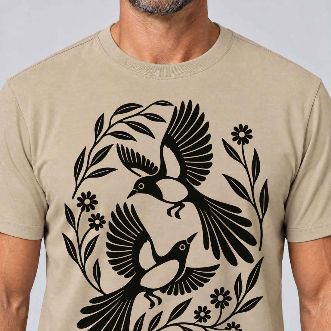Nahaufnahme des Drucks: Elsternpaar im Scherenschnitt – T-Shirt Unisex in Sand, von einem Mann getragen