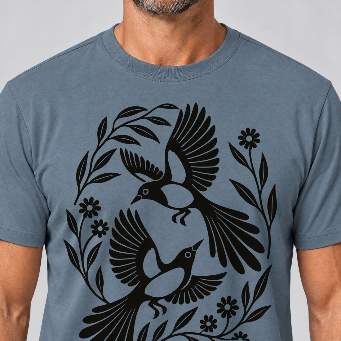 Nahaufnahme des Drucks: Elsternpaar im Scherenschnitt – T-Shirt Unisex in Steinblau, von einem Mann getragen