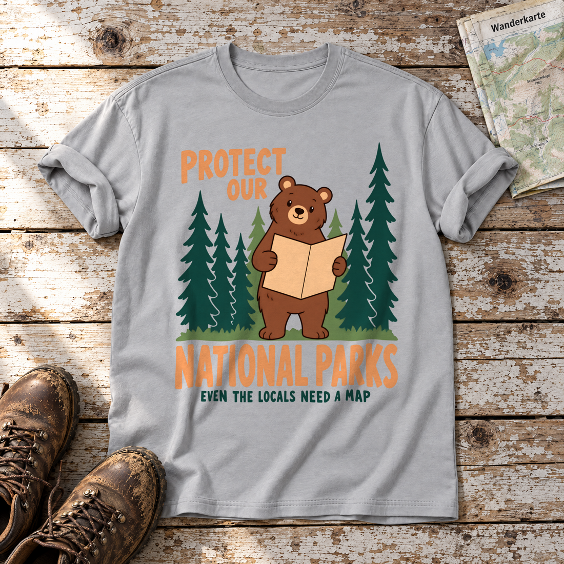 Even the Locals Need a Map – T-Shirt Unisex in Hellgrau, flach liegend auf alten Holzbrettern mit Wanderschuhen und Wanderkarte.