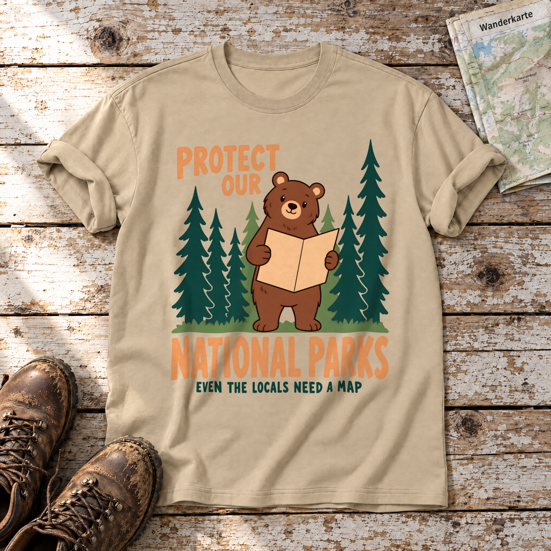 Even the Locals Need a Map – T-Shirt Unisex in Sand, flach liegend auf alten Holzbrettern mit Wanderschuhen und Wanderkarte.