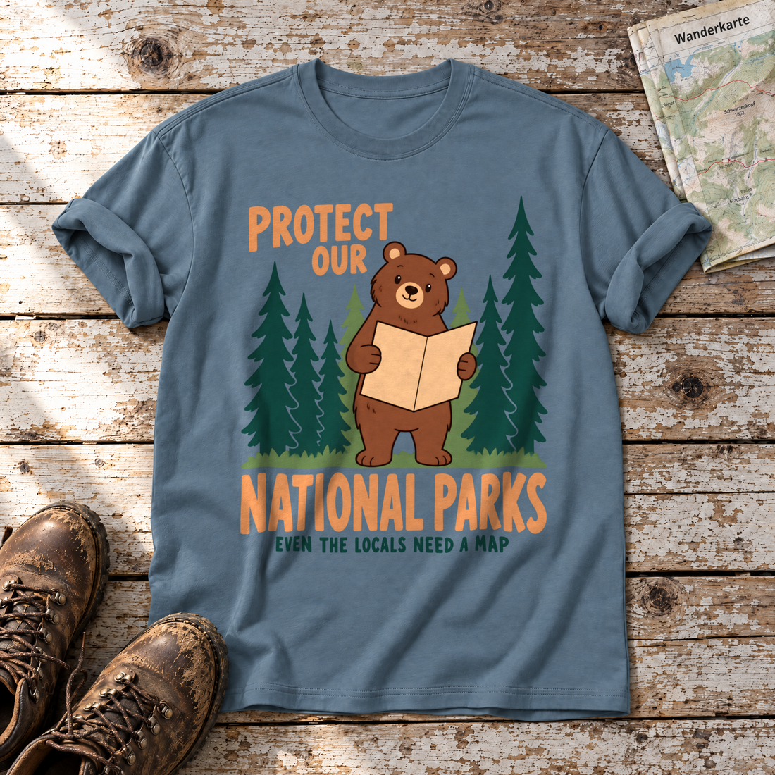 Even the Locals Need a Map – T-Shirt Unisex in Steinblau, flach liegend auf alten Holzbrettern mit Wanderschuhen und Wanderkarte.