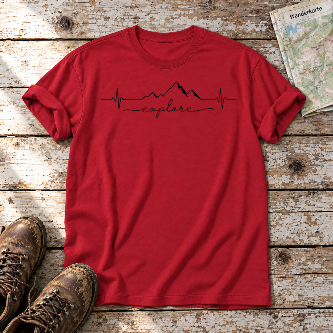 Explore Herzschlag – T-Shirt Unisex in Rot, flach liegend auf alten Holzbrettern mit Wanderschuhen und Wanderkarte.
