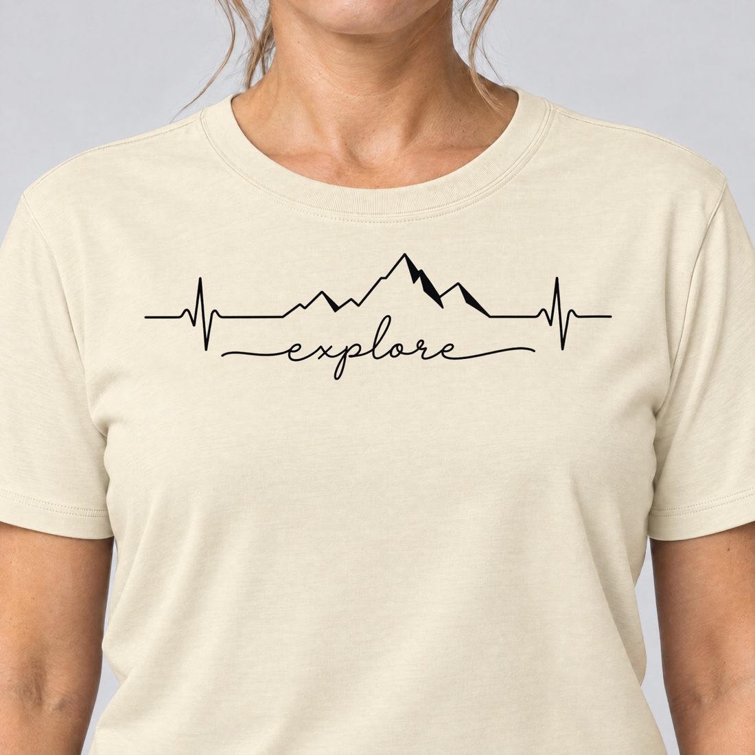 Nahaufnahme des Drucks: Explore Herzschlag – T-Shirt Unisex in Natur, von einer Frau getragen