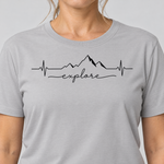 Nahaufnahme des Drucks: Explore Herzschlag – T-Shirt Unisex in Hellgrau, von einer Frau getragen