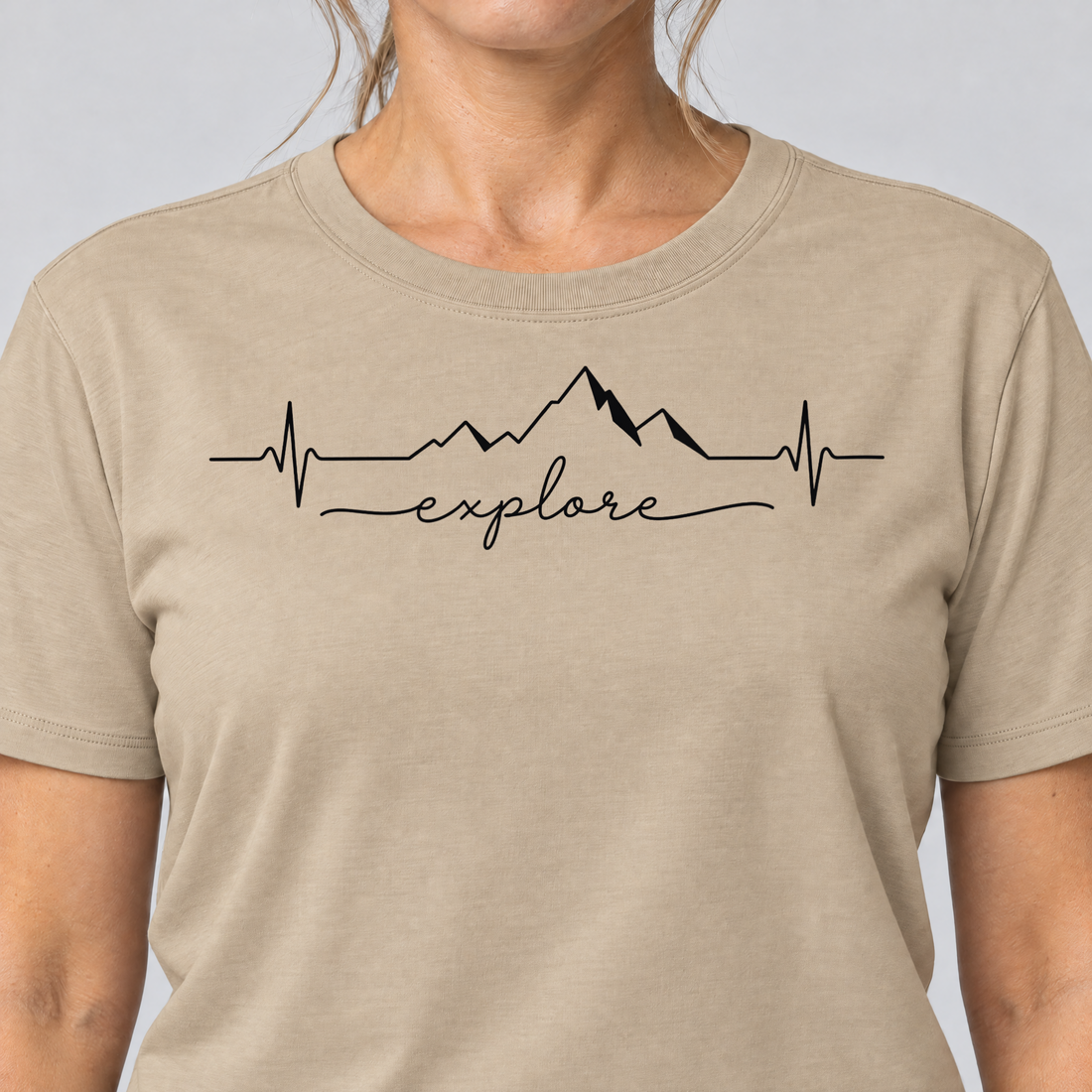 Nahaufnahme des Drucks: Explore Herzschlag – T-Shirt Unisex in Sand, von einer Frau getragen