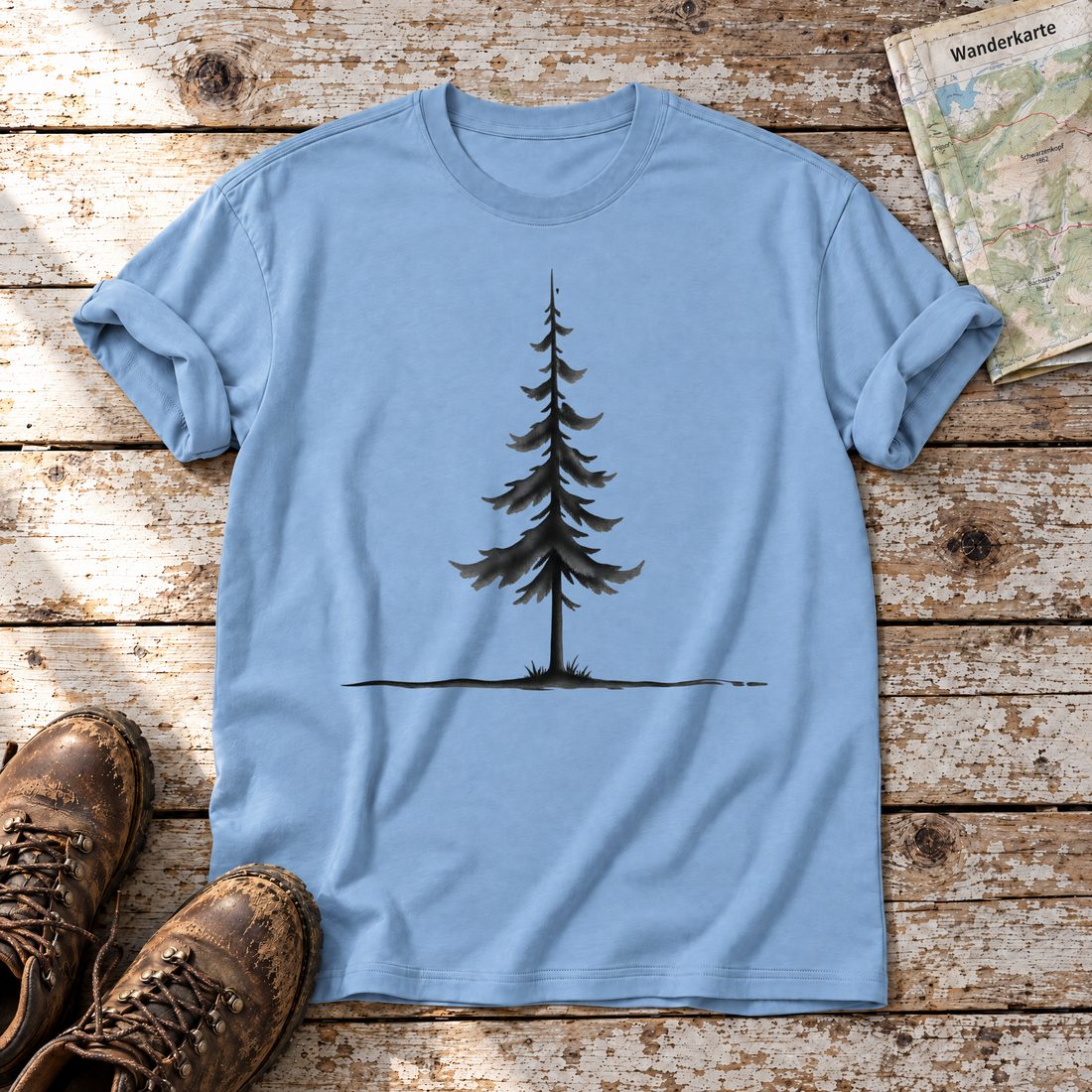 Fichte am Horizont – T-Shirt Unisex in Himmelblau, flach liegend auf alten Holzbrettern mit Wanderschuhen und Wanderkarte.