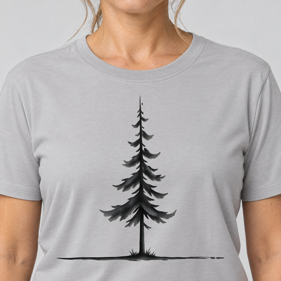 Nahaufnahme des Drucks: Fichte am Horizont – T-Shirt Unisex in Hellgrau, von einer Frau getragen