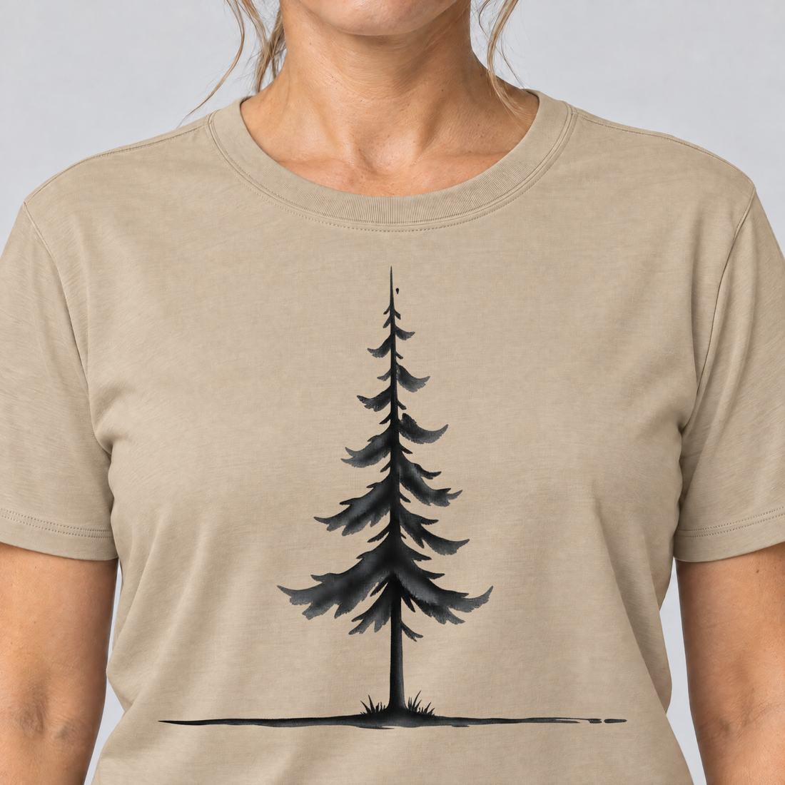 Nahaufnahme des Drucks: Fichte am Horizont – T-Shirt Unisex in Sand, von einer Frau getragen