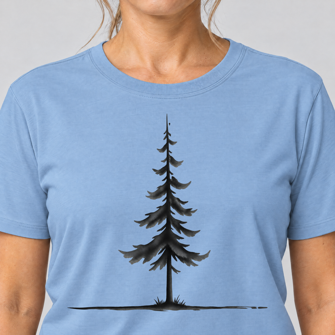 Nahaufnahme des Drucks: Fichte am Horizont – T-Shirt Unisex in Himmelblau, von einer Frau getragen