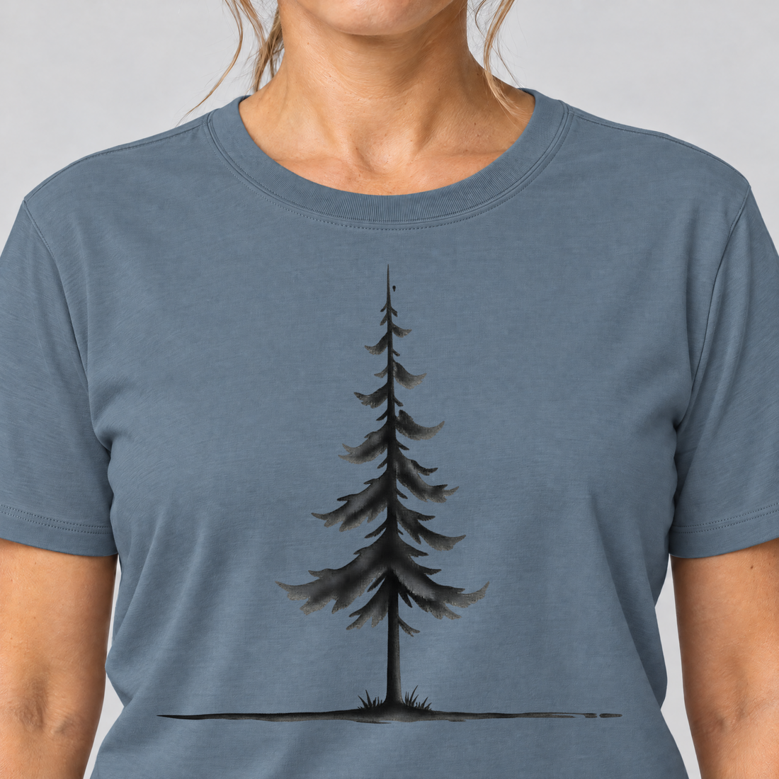 Nahaufnahme des Drucks: Fichte am Horizont – T-Shirt Unisex in Steinblau, von einer Frau getragen