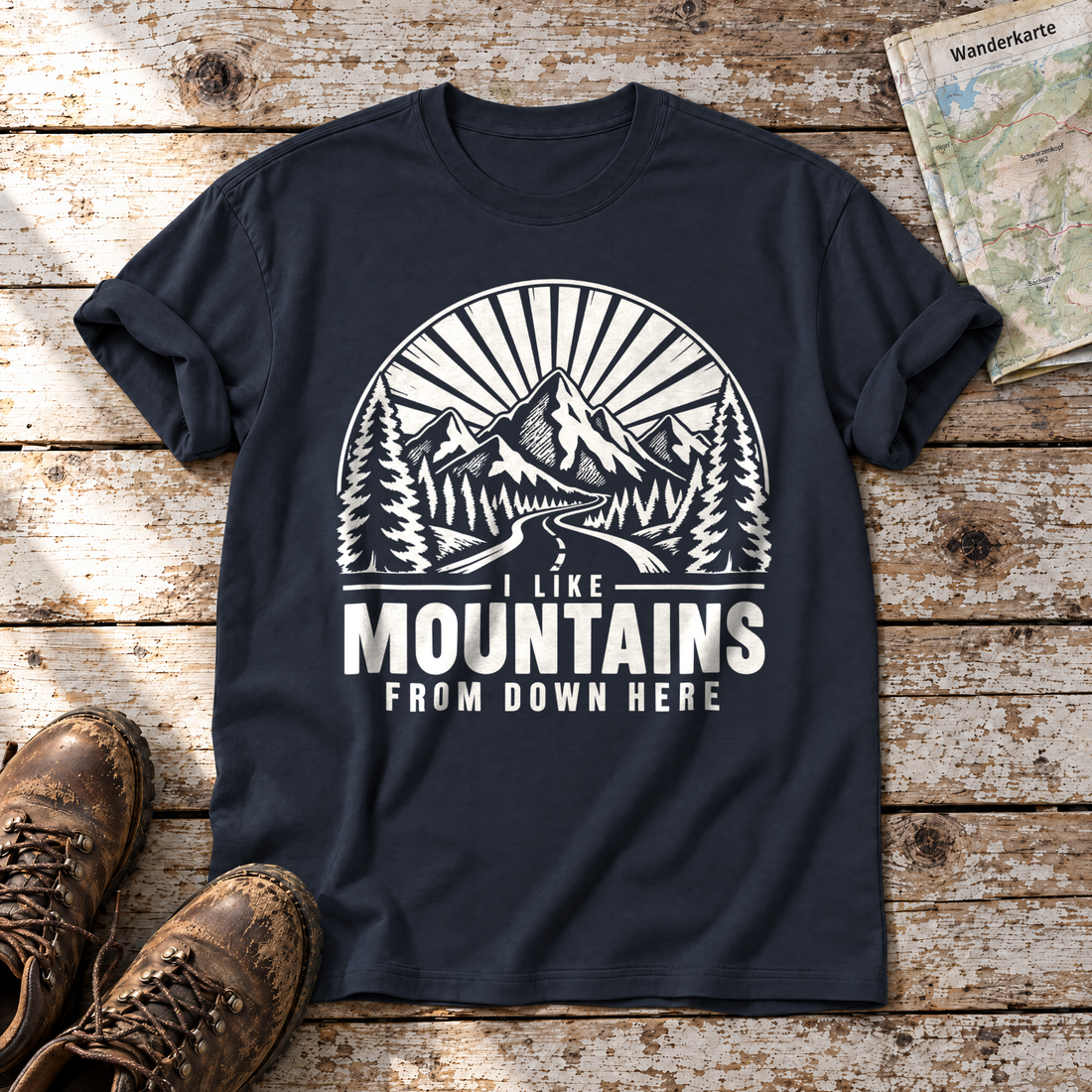 I like mountains from down here – T-Shirt Unisex in Navy, flach liegend auf alten Holzbrettern mit Wanderschuhen und Wanderkarte.