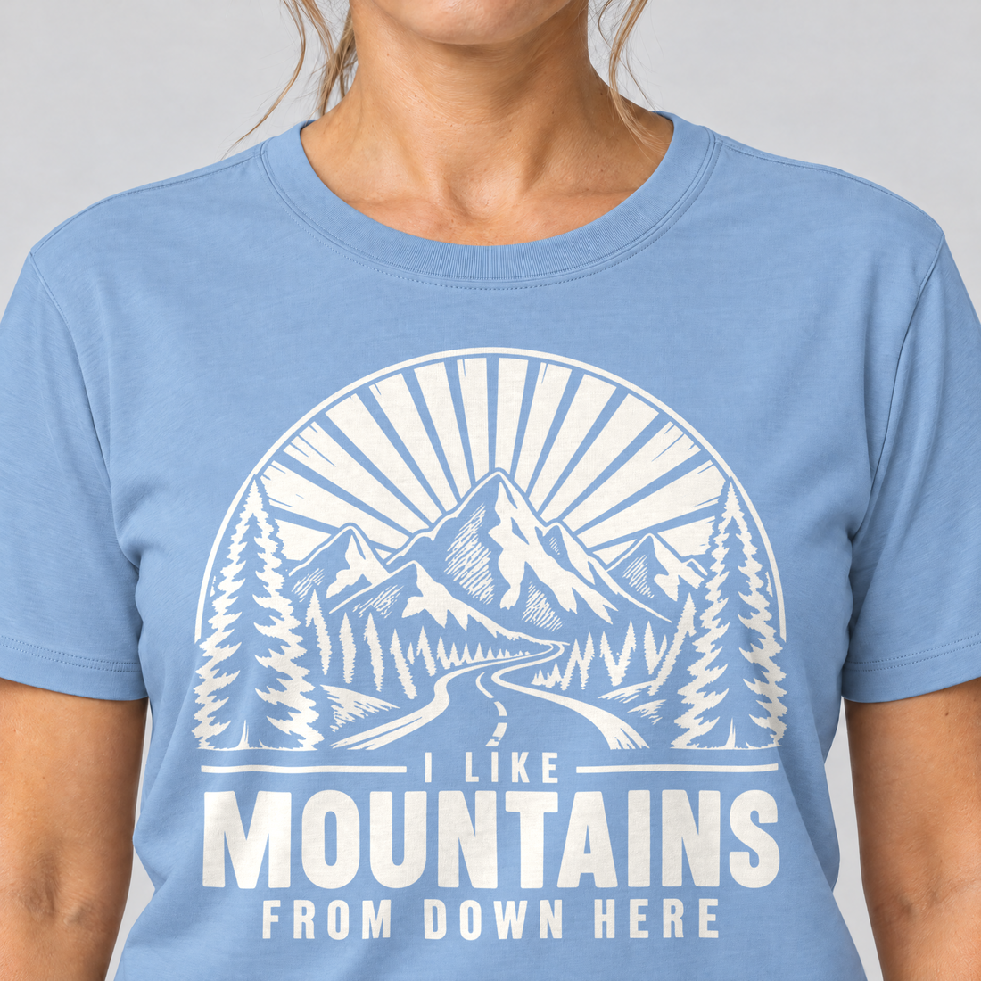 Nahaufnahme des Drucks: I like mountains from down here – T-Shirt Unisex in Himmelblau, von einer Frau getragen