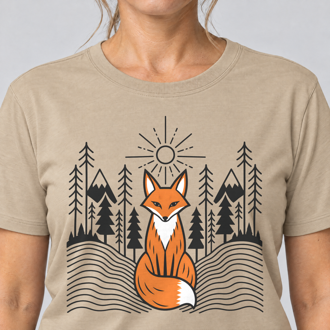 Nahaufnahme des Drucks: Fuchs im Tannenwald – T-Shirt Unisex in Sand, von einer Frau getragen