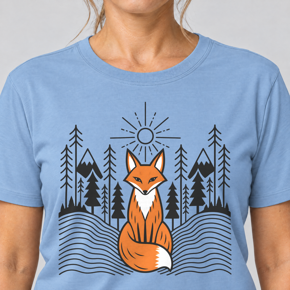 Nahaufnahme des Drucks: Fuchs im Tannenwald – T-Shirt Unisex in Himmelblau, von einer Frau getragen
